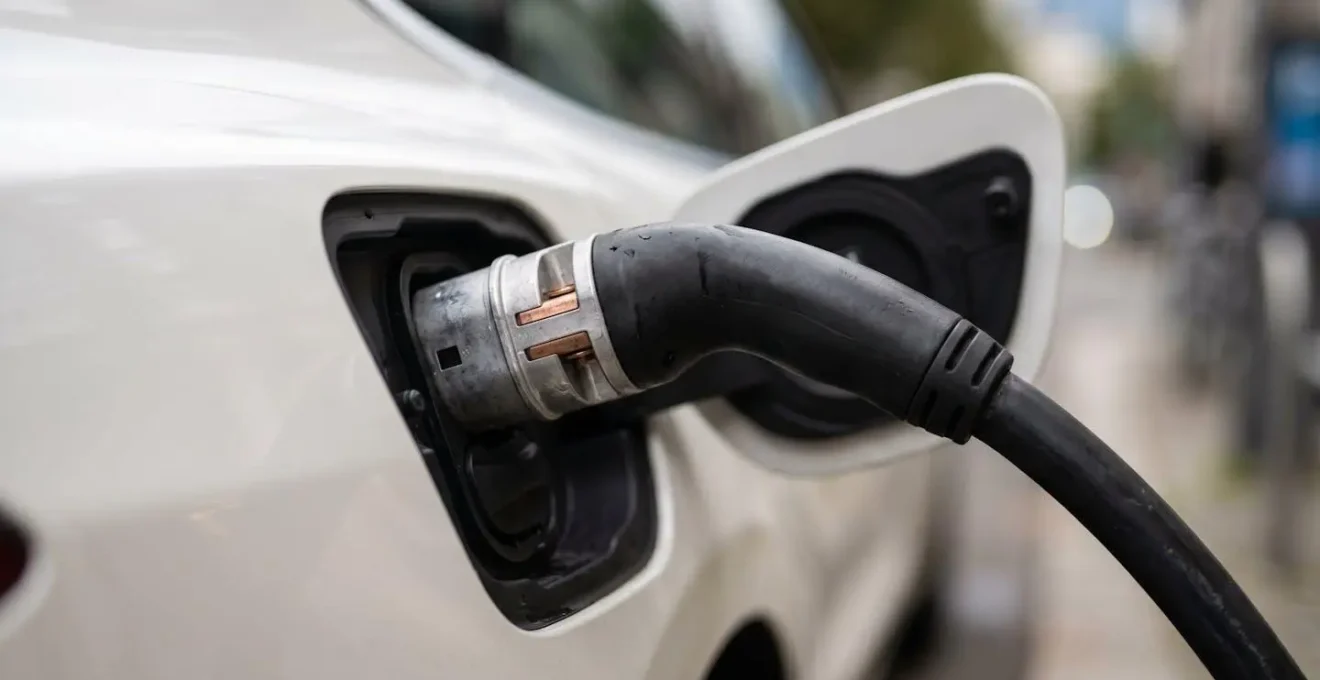 Véhicule électrique connecté à une borne de recharge dans un parking urbain